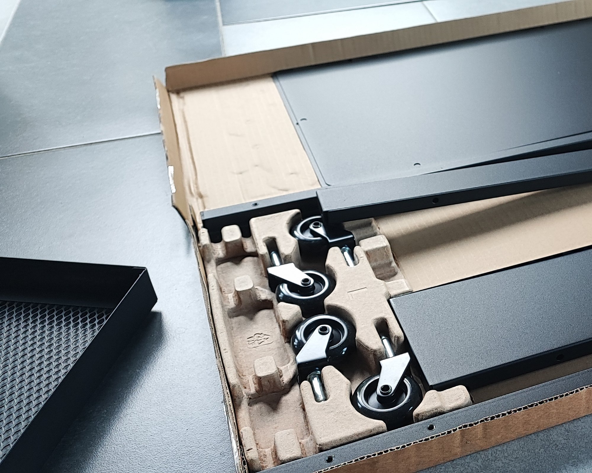 Geöffneter Karton mit Rollen und Bauteilen