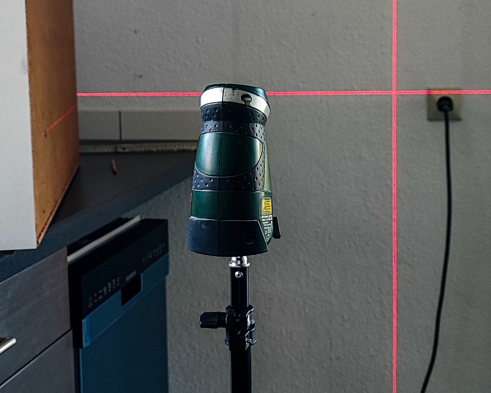 Kreuzlinien-Laser an der Wand neben einer Steckdose
