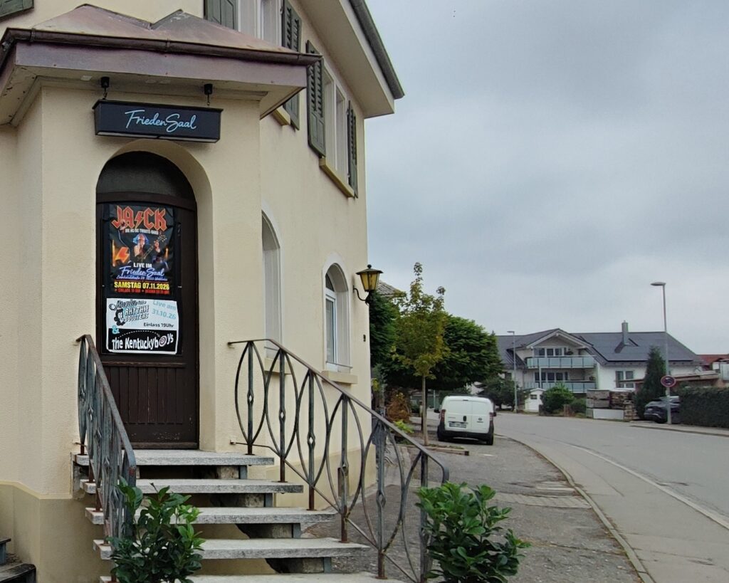 Eingang des Friedensaals in Wahlwies mit Leuchtschild über der Tür und Treppe