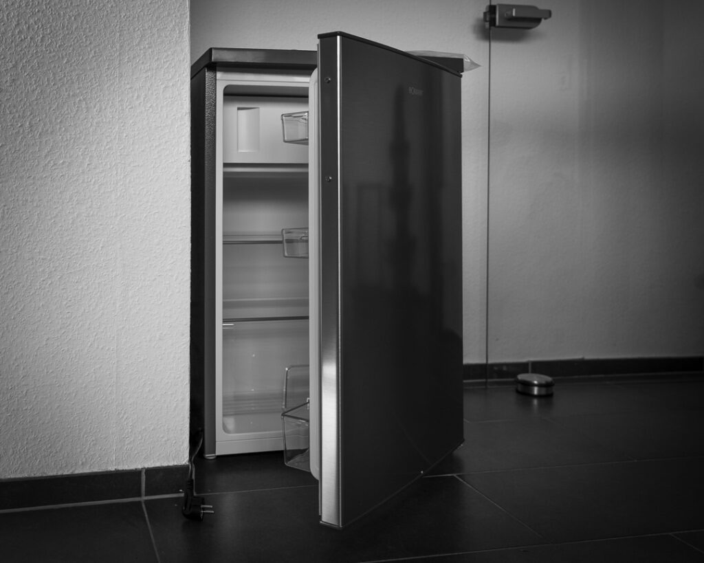 Neuer Kühlschrank mit kleinem Gefrierfach und geöffneter Tür in der Küche der Ferienwohnung Wahlwies, Schwarzweißfoto