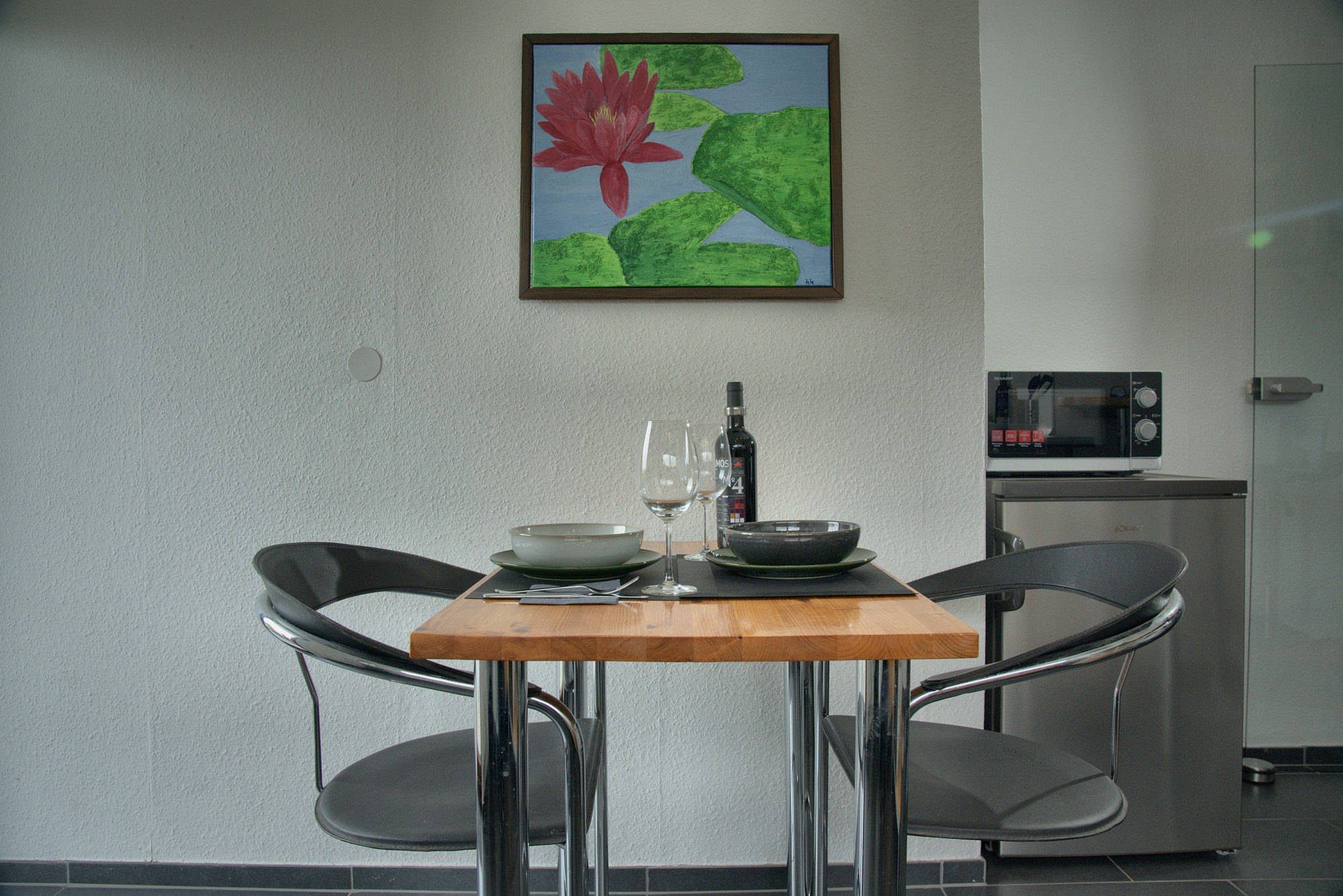 Gedeckter Esstisch für zwei mit Seerosen-Bild an der Wand